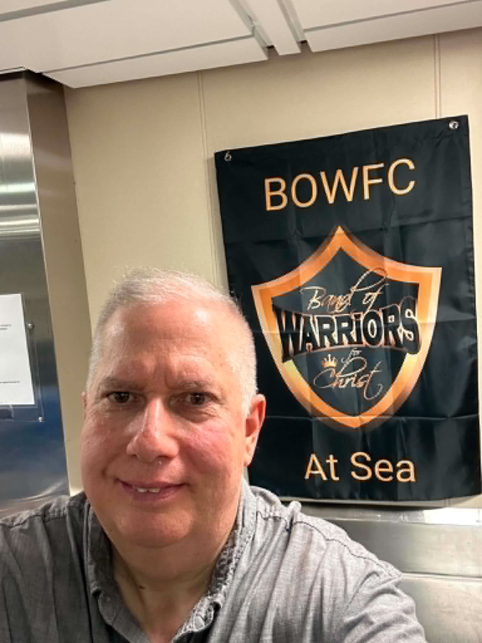 Elder Jeffery Gill standing beside the BOWFC at Sea banner